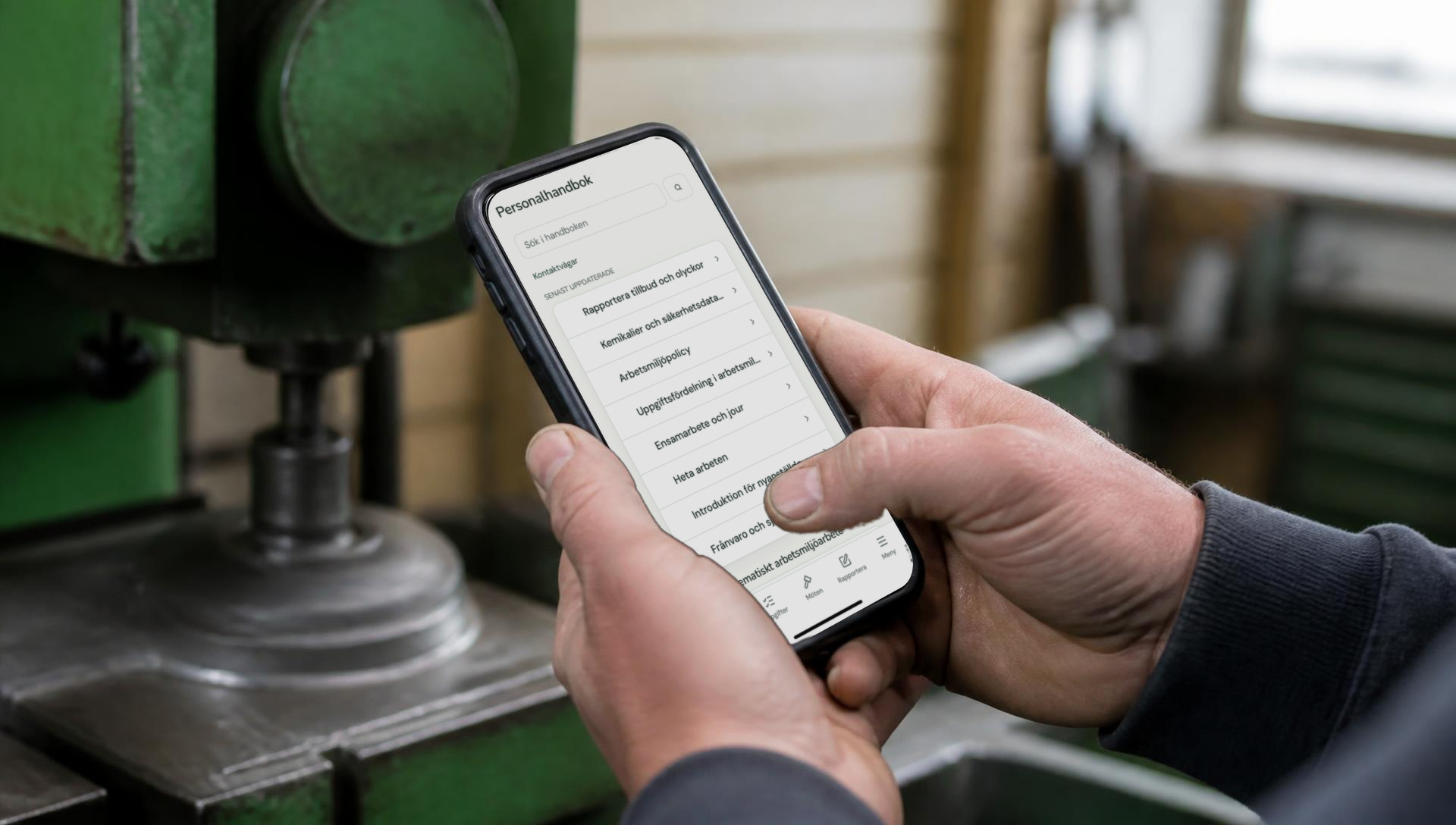 Verkstadsarbetare läser personalhandboken i FlowWorks app